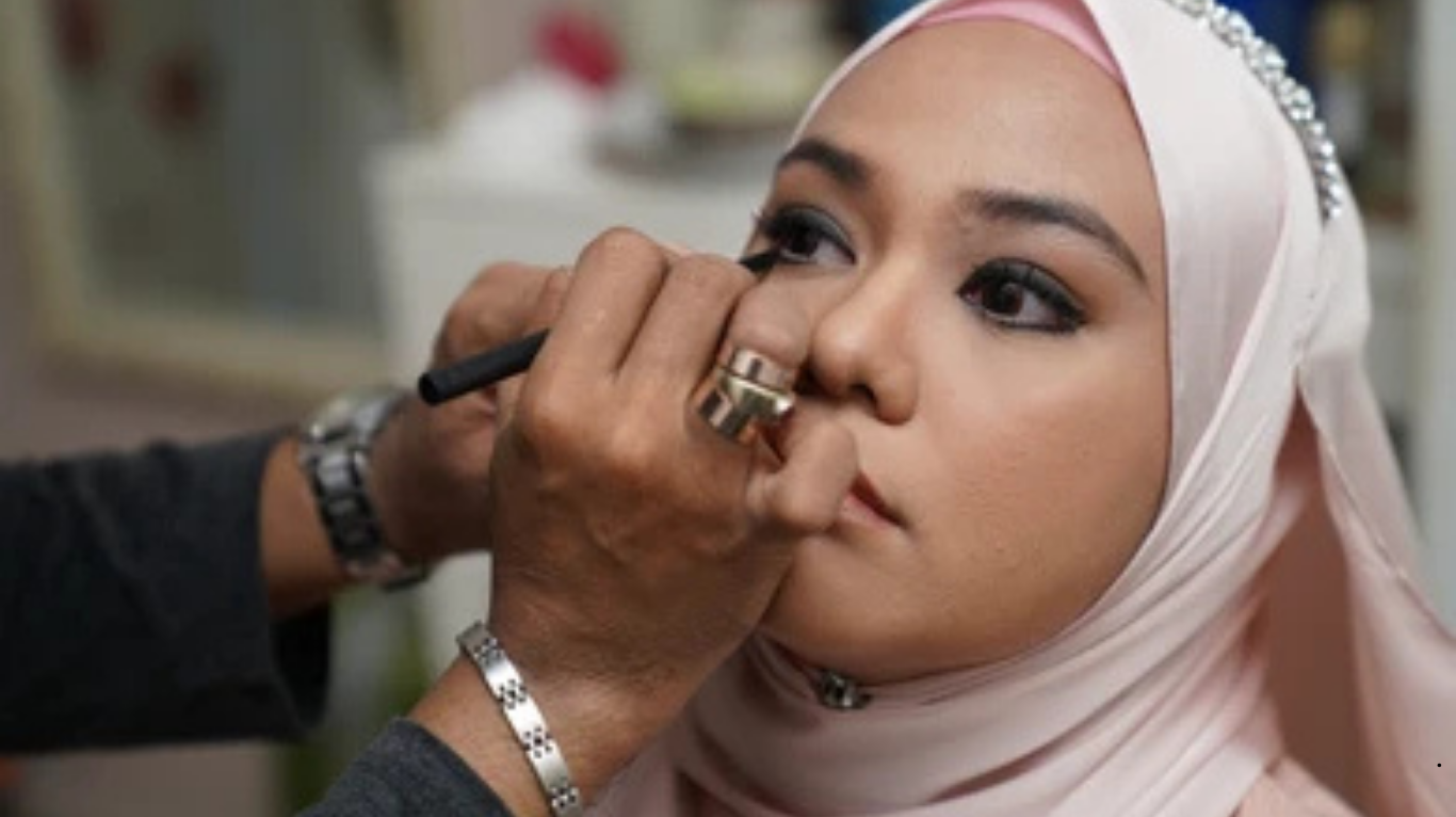 Bridal makeup artist applying lipstick to bride